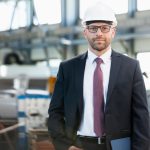 Portrait of confident mid adult businessman wearing hardhat in metal industry
