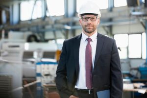 Portrait of confident mid adult businessman wearing hardhat in metal industry